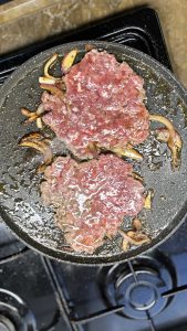 בשר הסמאש בורגר במחבת לוהטת עם רצועות בצל מקורמל