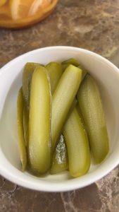 מלפפון חמוץ חתוך לרצועות לסמאר בורגר בקערה לבנה