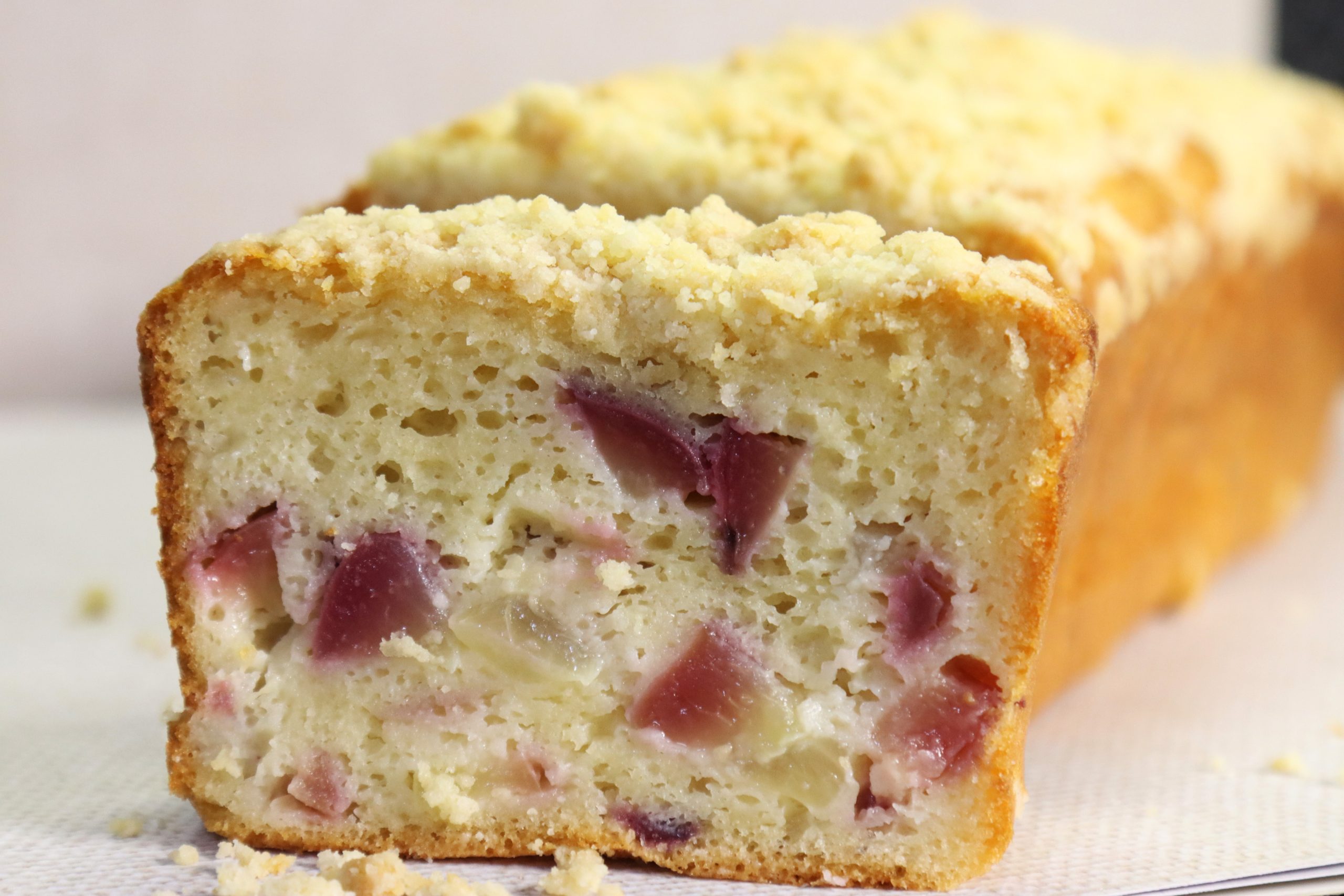 פרוסת עוגת נקטרינה בחושה עם פירורים ומאחוריה ברקע העוגה עצמה