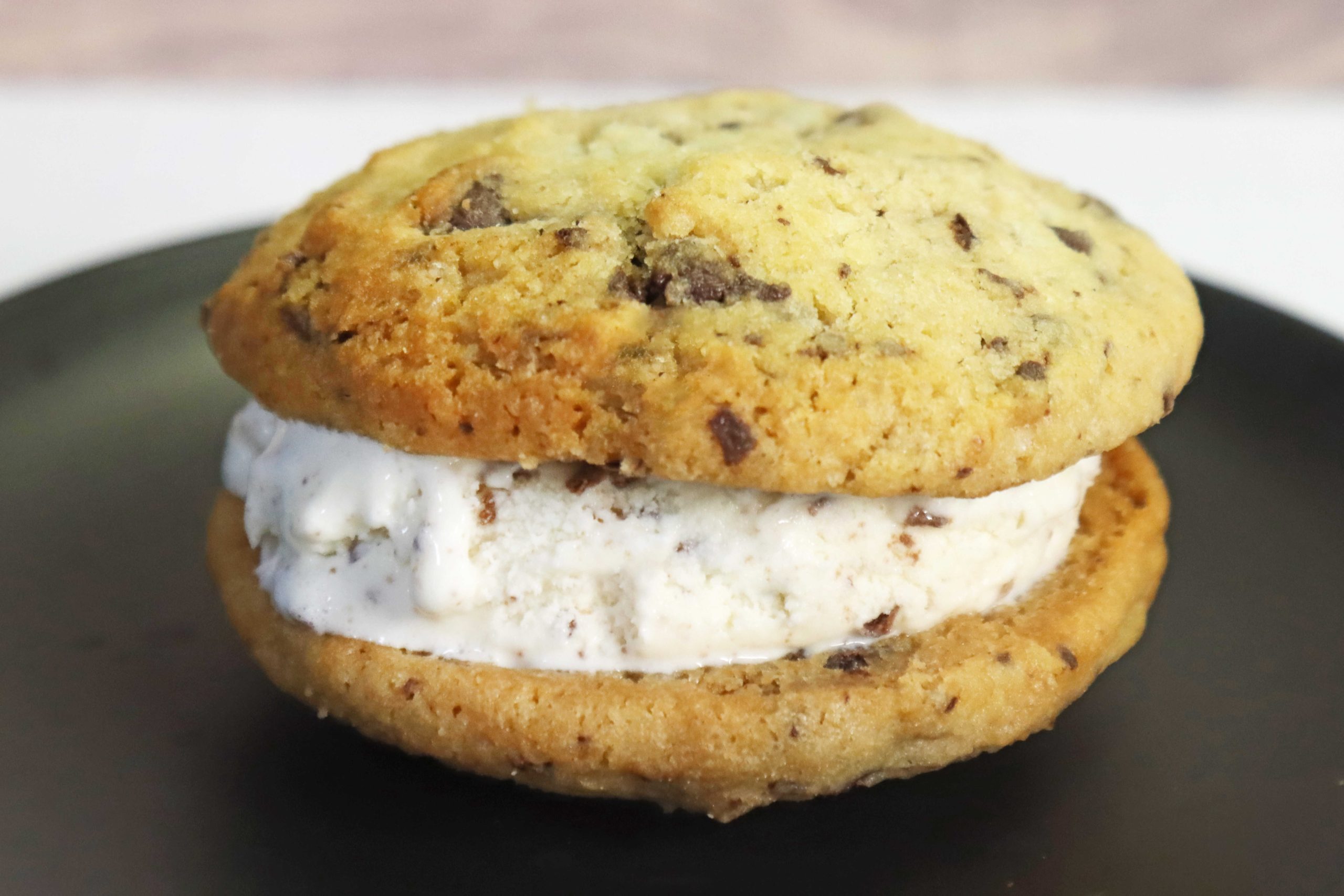 גלידת וניל עם פצפוצי שוקולד בתוך עוגיות שוקולד צ'יפס, על גבי צלחת שחורה