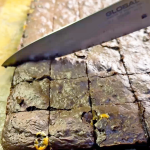 חיתוך בראוניז לקוביות בעזרת סכין חדה על גבי קרש עץ