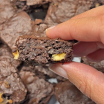 יד אוחזת בריבוע בראוניז עם שוקולד לבן קצוץ