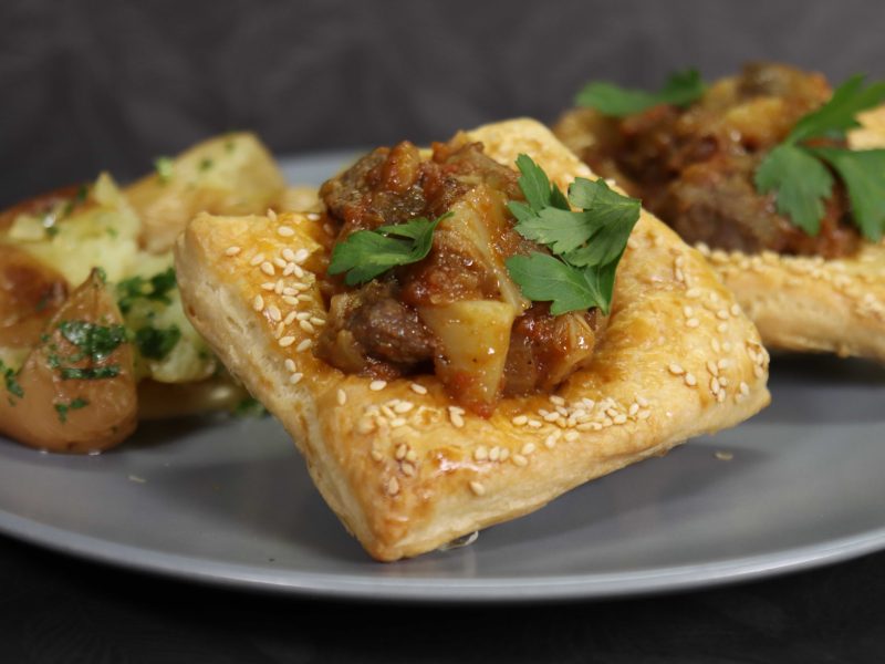 ריבועי בצק פריך עם תבשיל אונטריב ותפוחי אדמה מעורכים על צלחת אפורה