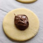 עיגול בצק פריך עם כף נוטלה לפני האפייה