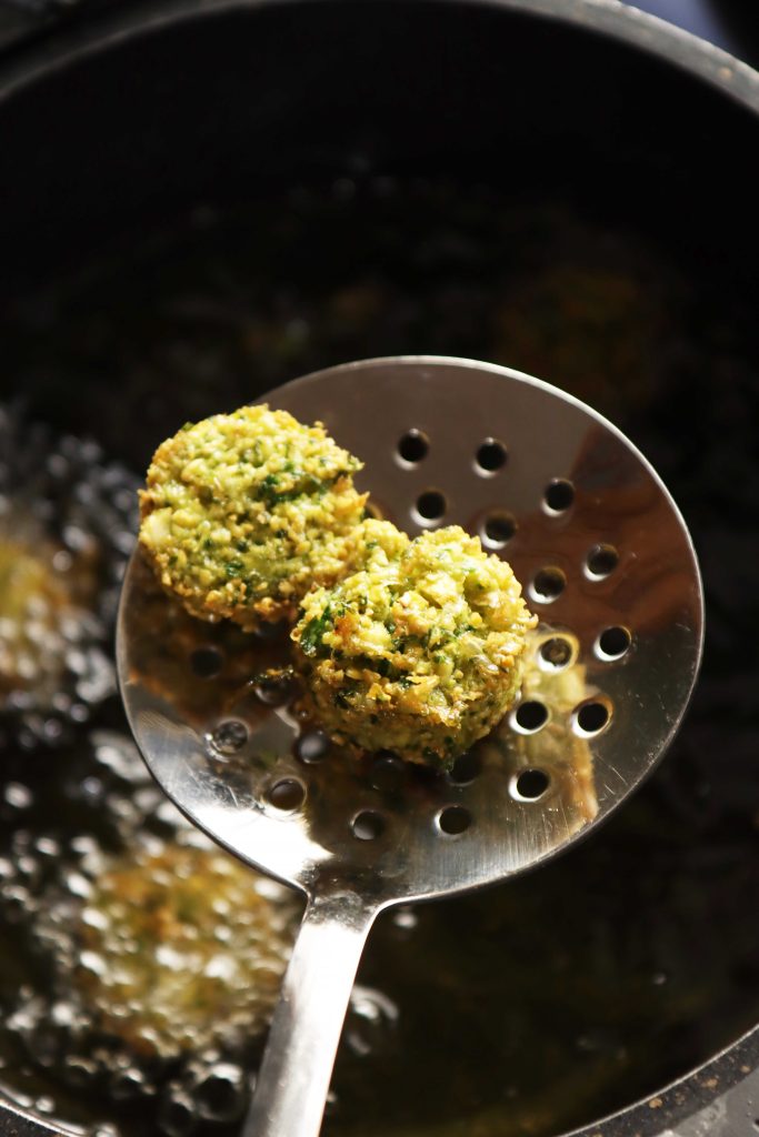 כדורי הפלאפל יוצאים מסיר השמן הלוהט בעזרת כף מתכת מחוררת